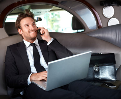 Smiling handsome businessman sitting in luxury limousine