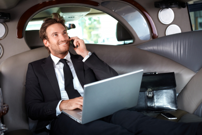 Smiling handsome businessman sitting in luxury limousine