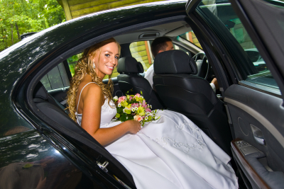 Bride sitting in a black wedding limousine
